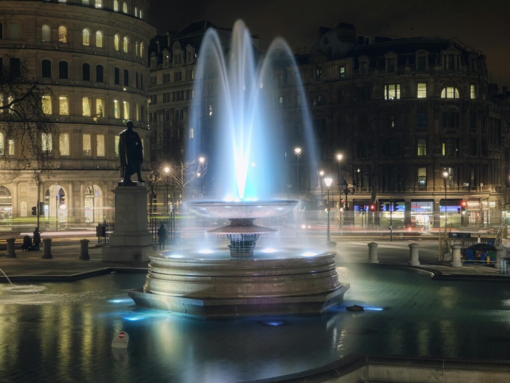 Stunning night view of the illuminated fountain in Trafalgar Square, London.
