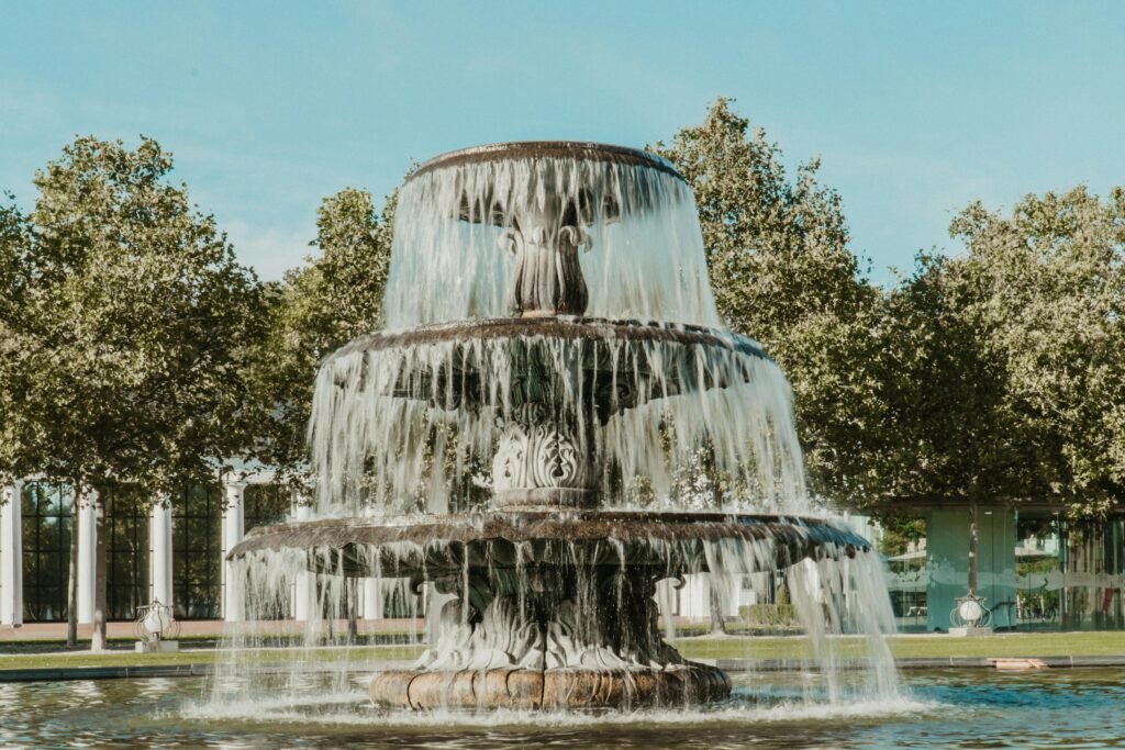 A beautiful tiered fountain surrounded by green trees in a Wiesbaden park, Germany.